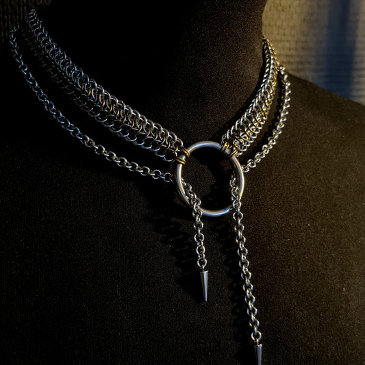 Necklace with multiple chains and a central ring on a black background