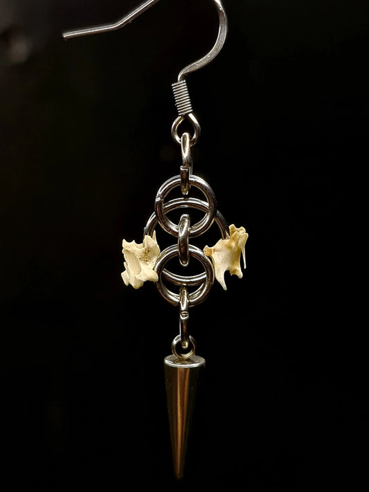 Earring with spiral design, bird bones, and spike on a black background
