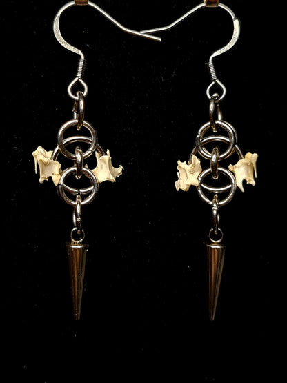 Pair of earrings with bird bones and spikes on a black background