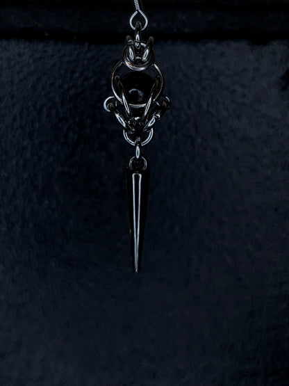 Silver pendant with a black bead on a black background