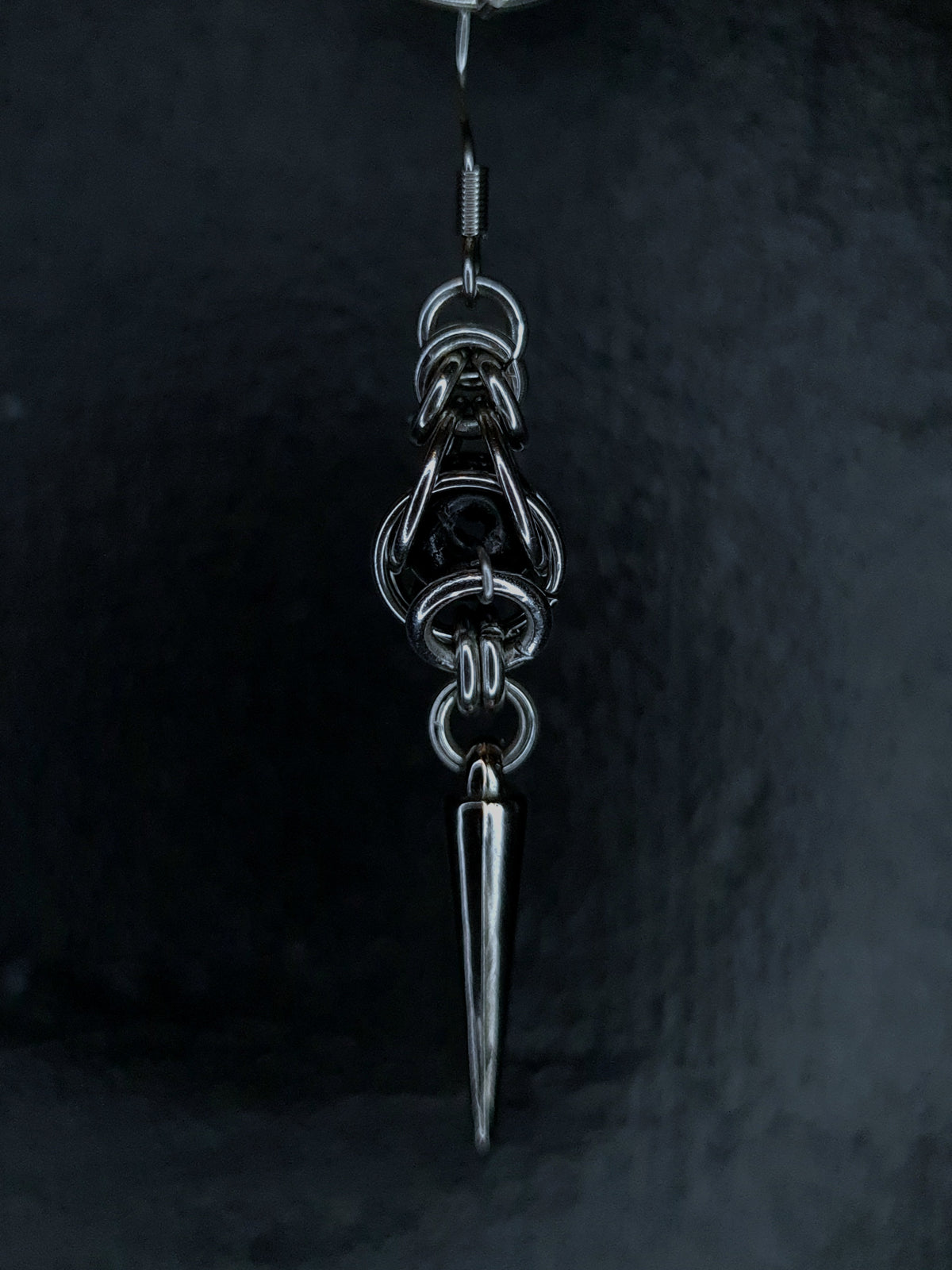Silver pendant with a sharp point on a dark background