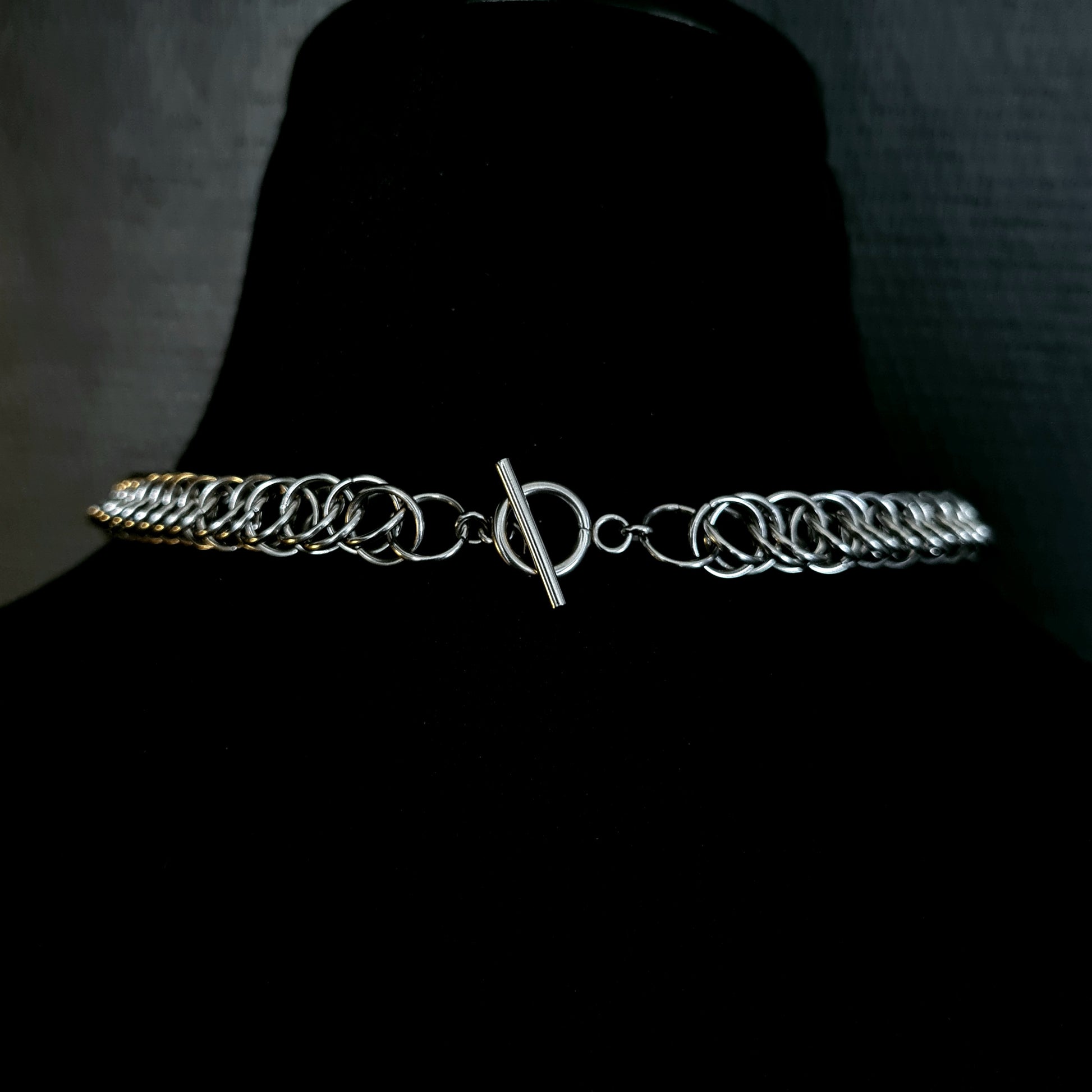 Silver chain belt on a black mannequin against a dark background