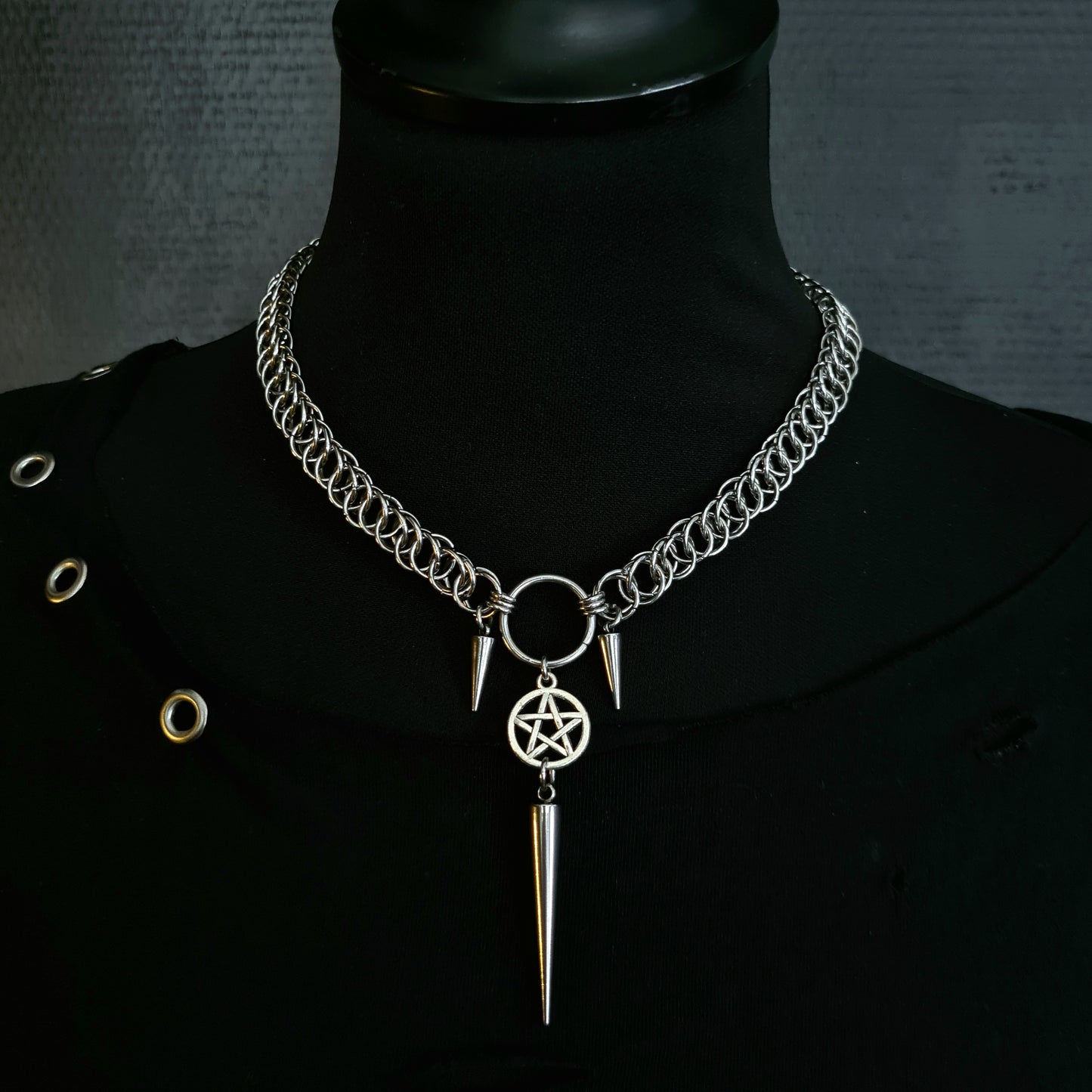 Necklace with pentagram and spike pendant on a black mannequin against a dark background