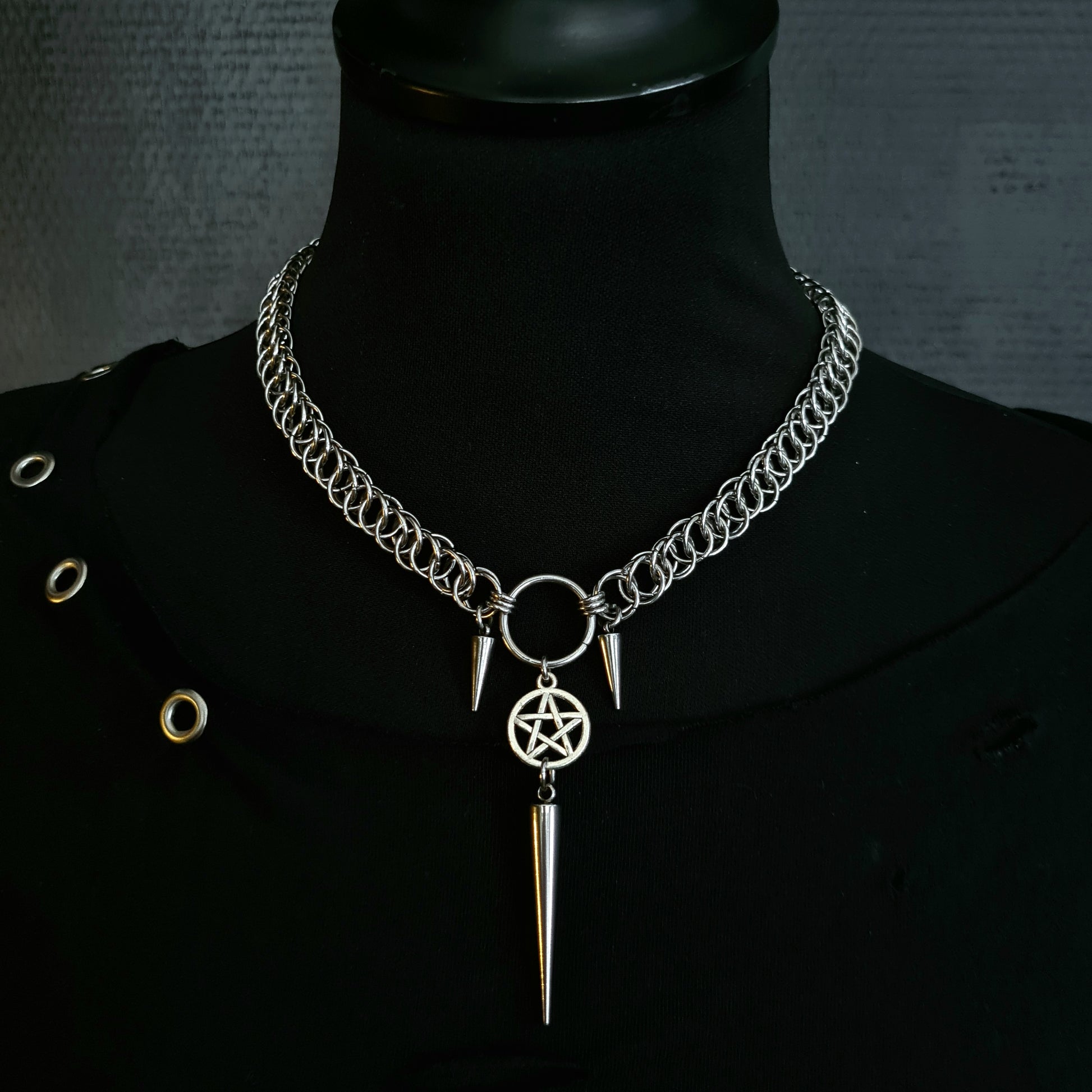 Necklace with pentagram and spike pendant on a black mannequin against a dark background