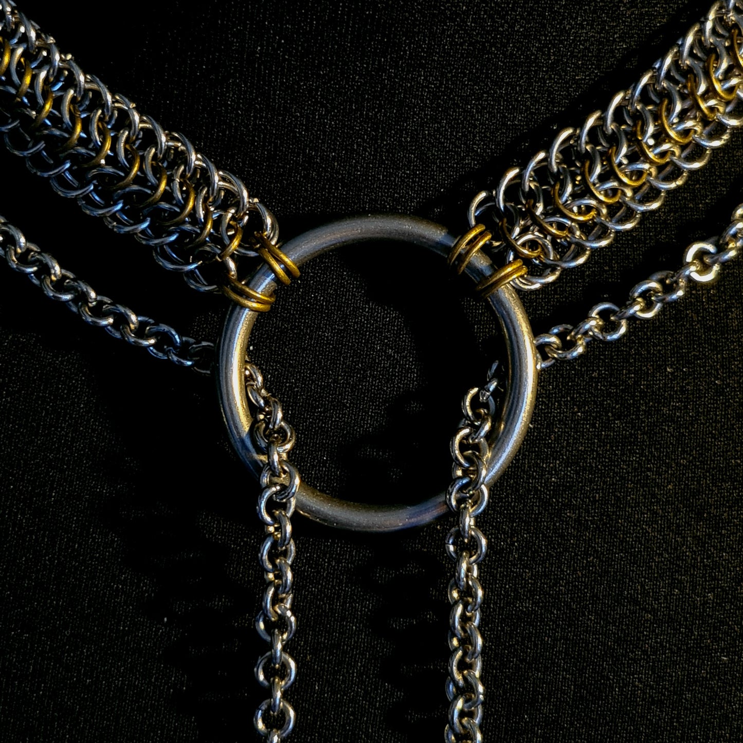 Close-up of a chain necklace with a central ring on a black background