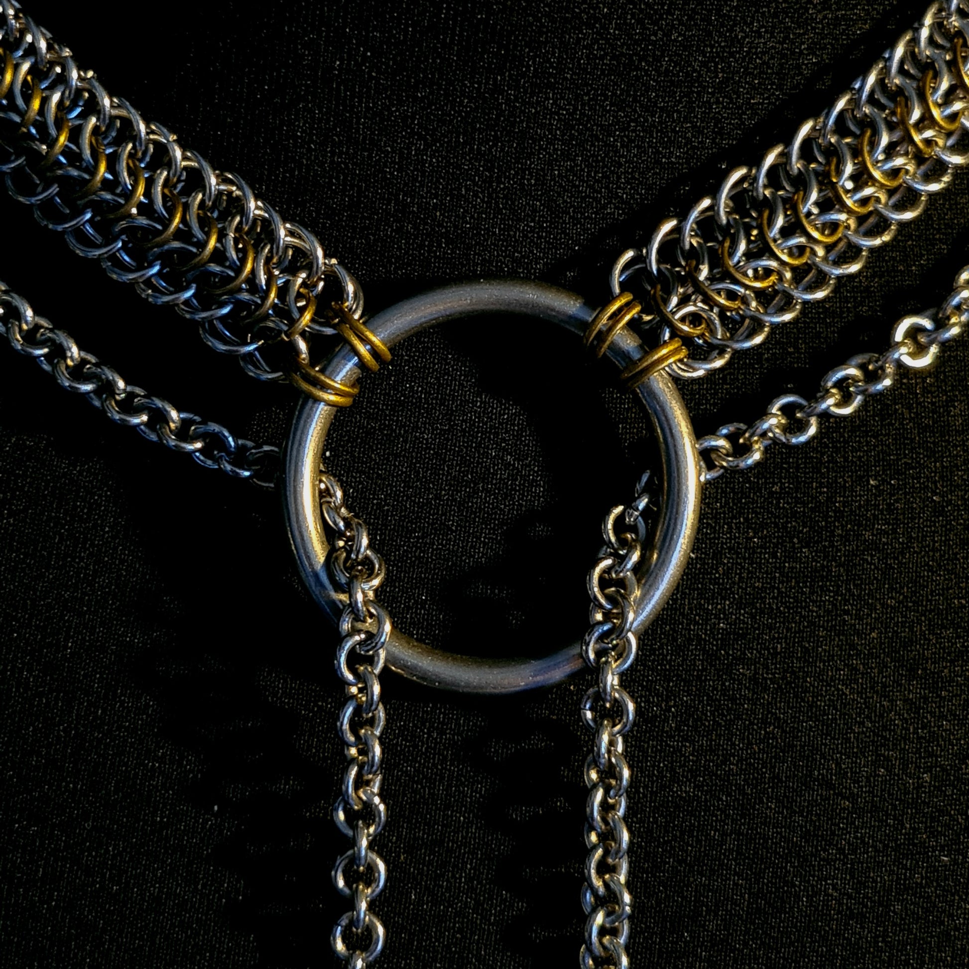 Close-up of a chain necklace with a central ring on a black background