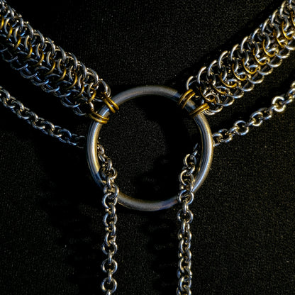 Close-up of a chain necklace with a central ring on a black background