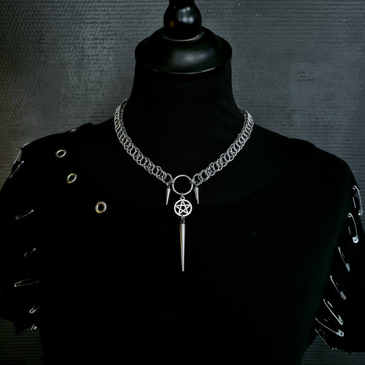 Mannequin wearing a silver chain necklace with a pendant on a dark background