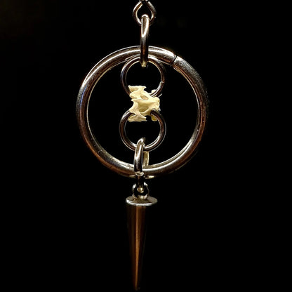Bird spike bone connecting two rings and a spike surrounded by an O ring on a black background