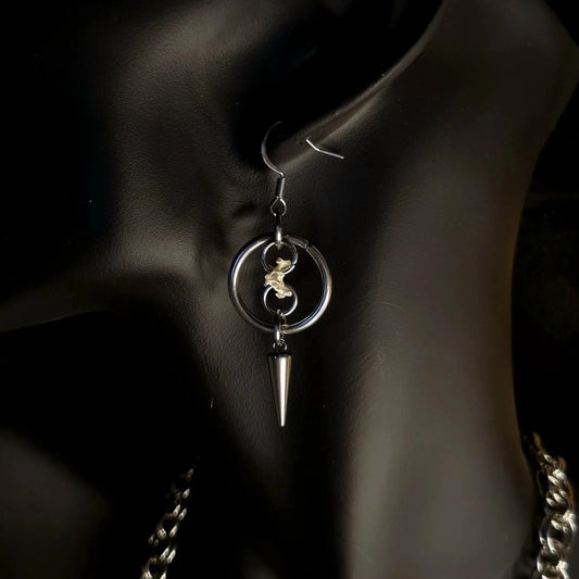 O Ring surrounding a chain holding a spine bone with a spike on an earring and black background