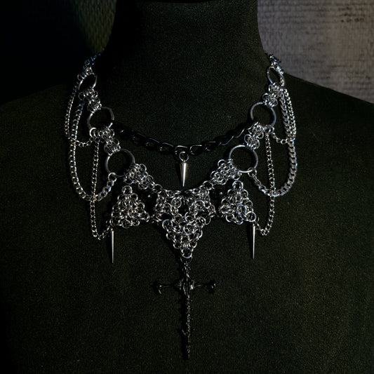 Gothic-style necklace choker with chains and spikes and cross on a black background