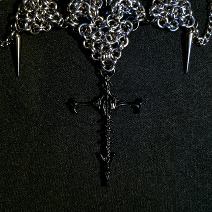 Necklace with chain, spikes, and a black spine cross pendant on a black background