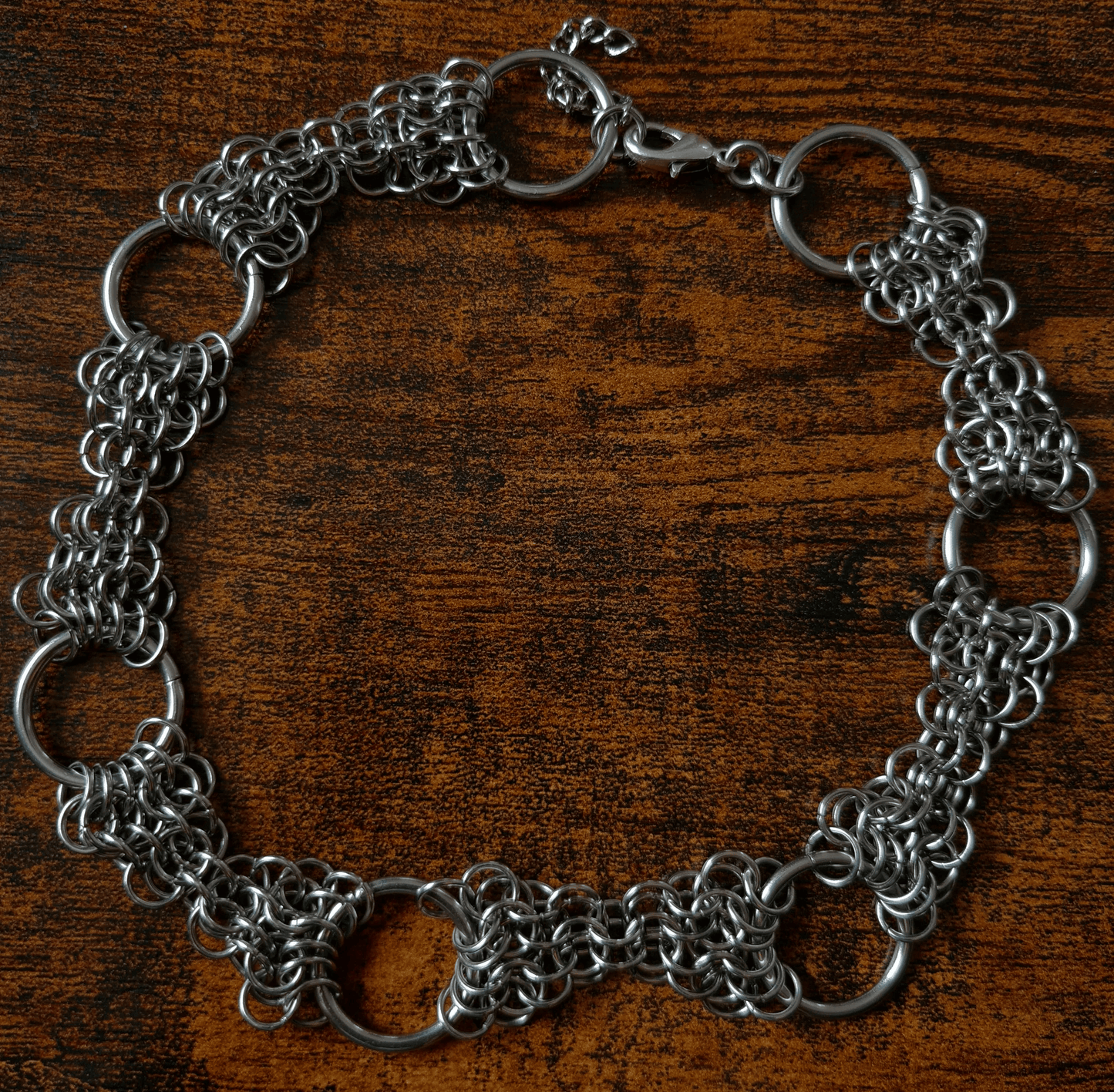 Metal chain choker necklace on a wooden surface