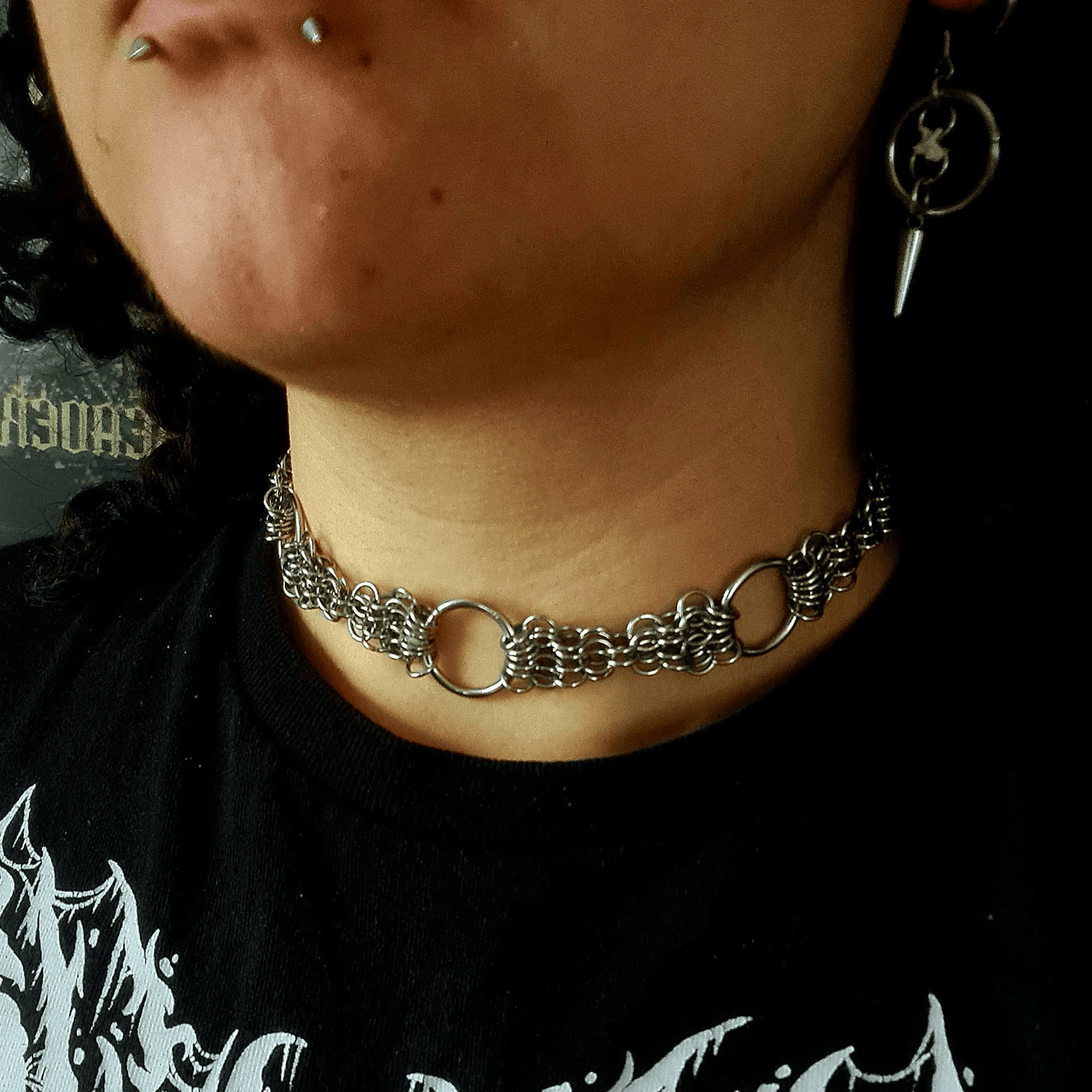 Close-up of a person wearing a chain necklace with a black shirt in the background
