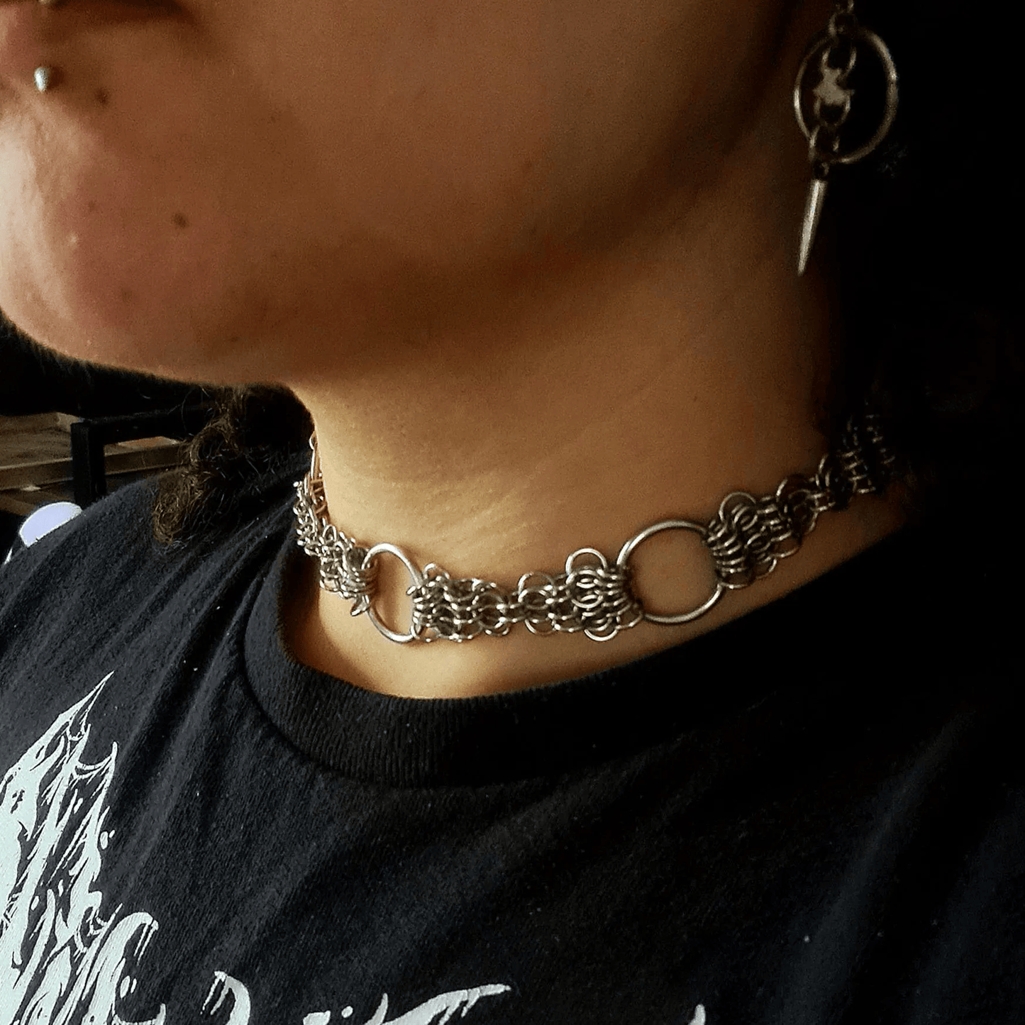 Person wearing a chain choker necklace with a black shirt.